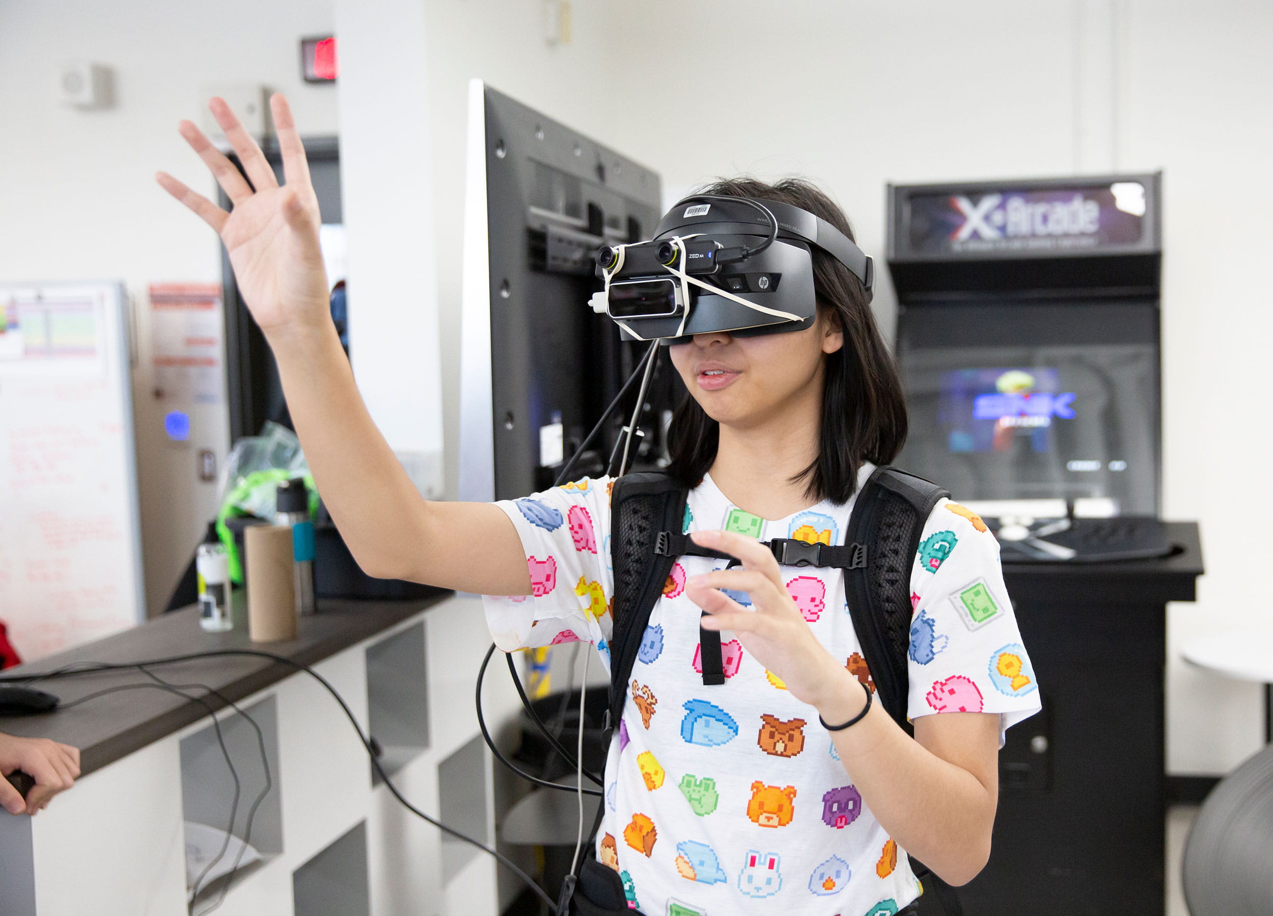 A young woman wearing a virtual reality headset and reaching out with her hand